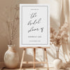 Printable bridal shower welcome sign on an easel with floral arrangements in a room setting.