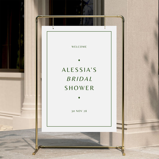 Welcome sign for a bridal shower with a gold stand against a neutral wall.