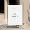 Welcome sign for a bridal shower with a gold stand against a neutral wall.