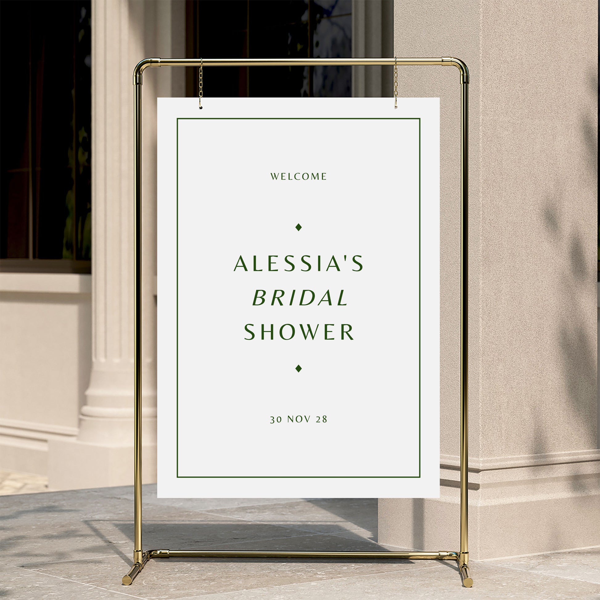 Welcome sign for a bridal shower with a gold stand against a neutral wall.