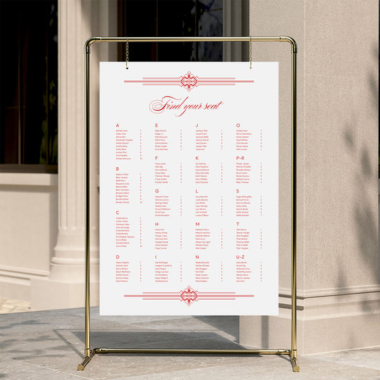 Alphabetical wedding seating chart template displayed on a gold stand against a neutral wall.