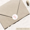 Brown kraft envelope with a white and red envelope sticker seal on white linen background.