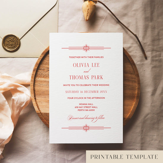 Red old money style wedding invitation template design on a white card sitting on a wooden plate with decorative elements.