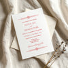 Old-world style wedding invitation card on textured card with envelope on fabric background.