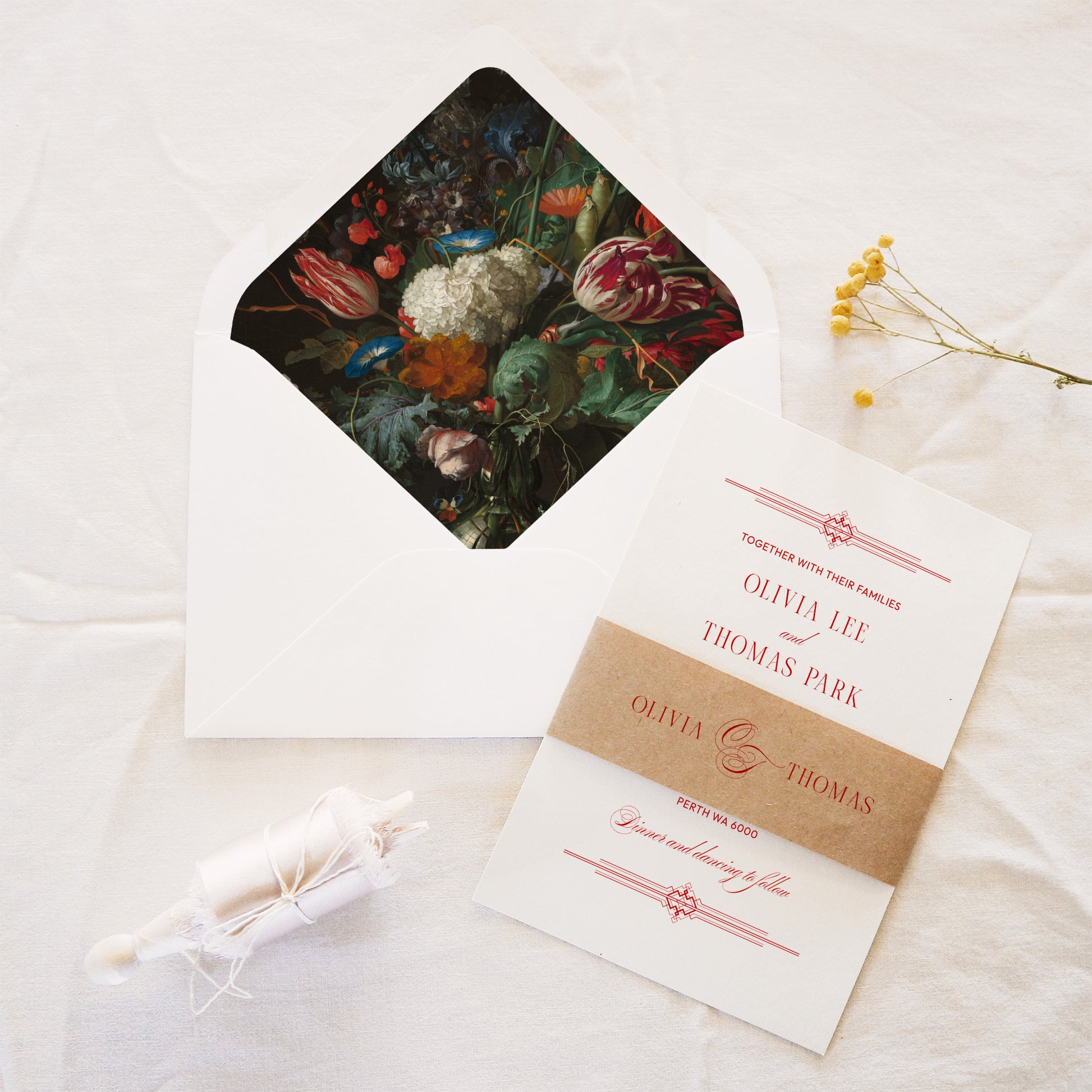 Wedding invitation with belly band and an open envelope with a patterned liner on a linen surface.