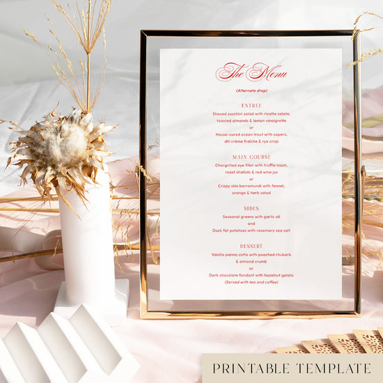 Printable wedding menu template in a gold frame on a soft pink tablecloth with dried florals and modern decorative accents.