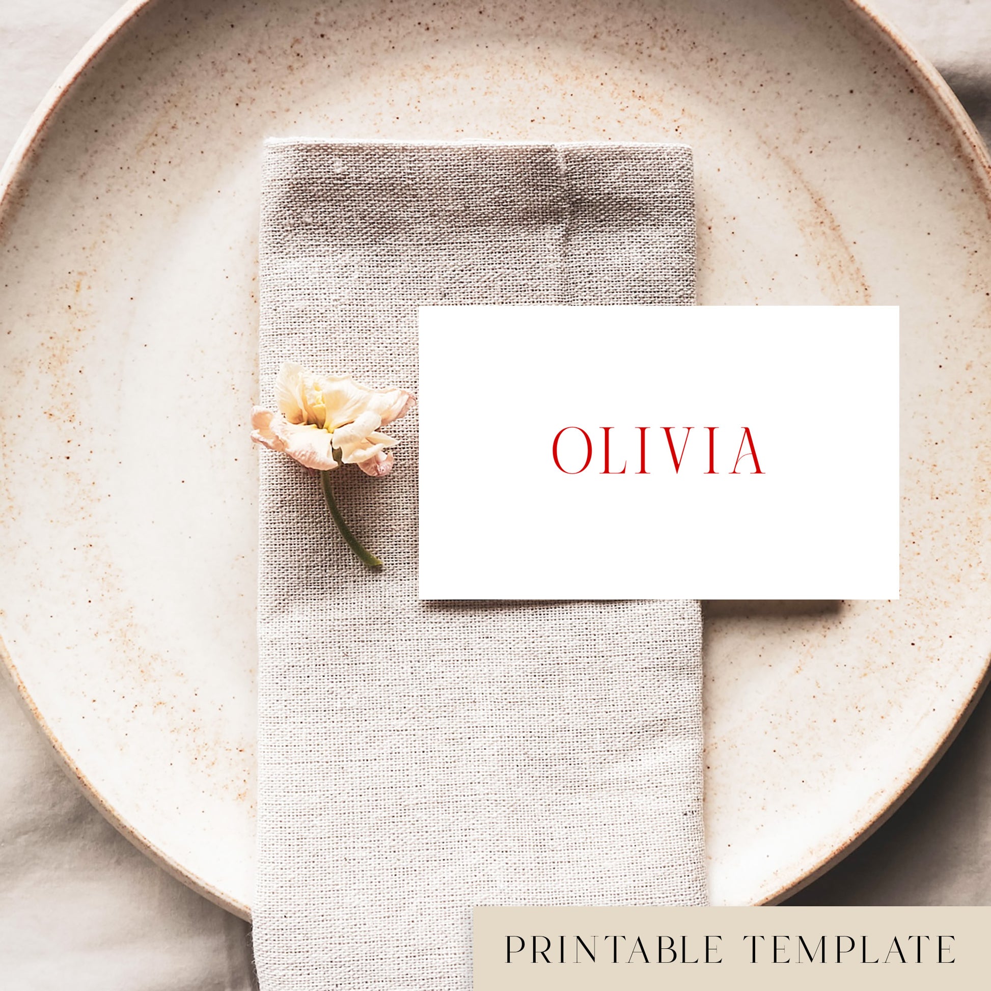 A flat place card with a name printed on it, positioned on a plate with a napkin and a floral decoration.