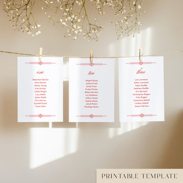 Three white seating chart cards with printed names, clipped to a string with pegs, against a neutral background.