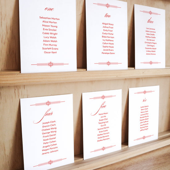 Set of six printable seating chart cards with names on a wooden display shelf.