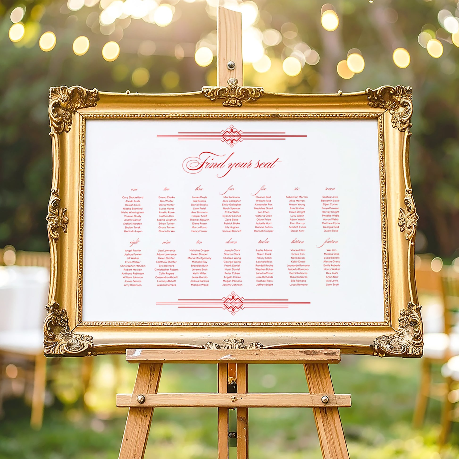 Decorative gold frame on an easel with a horizontal wedding seating chart outdoors.