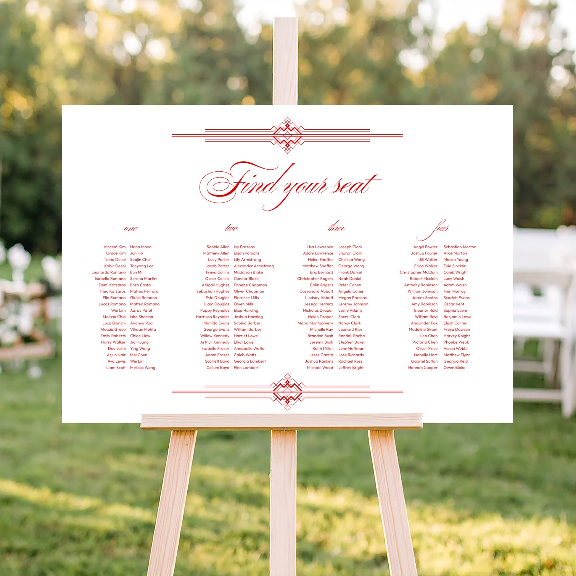 Horizontal wedding seating plan sign on an easel with a blurred outdoor ceremony background.