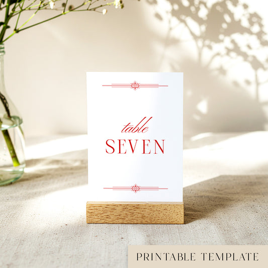 Printable table number card displayed on a wooden stand with a blurred natural background.