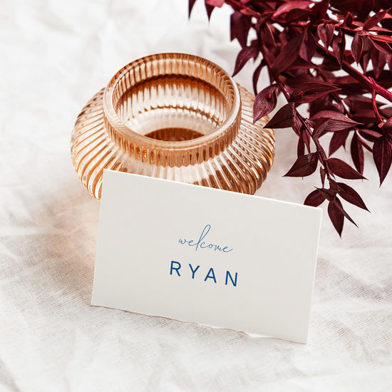Rose gold candle holder with a white place card leaning against it.