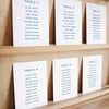 Set of six printable seating chart cards with names on a wooden display shelf.