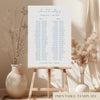 Printable minimal wedding seating chart sign on an easel with floral arrangements in a room setting.