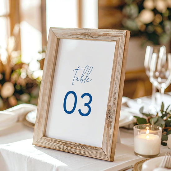 Printable table number card displayed on a wooden stand on a linen table cloth.