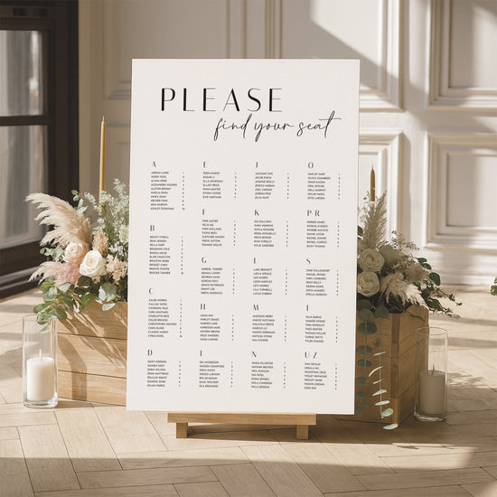 Modern alphabetical seating chart for a wedding with floral arrangements and candles in a room.