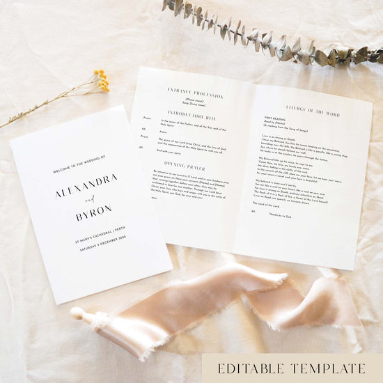 A5 wedding Mass ceremony booklet shown open with the cover beside it, styled on light fabric with dried florals and a soft ribbon.