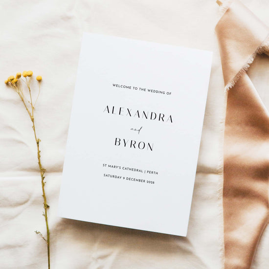 A5 wedding Mass ceremony booklet cover, photographed on light fabric with minimal floral styling.