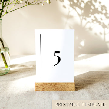 Printable table number card displayed on a wooden stand on a linen table cloth.