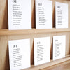 Set of six printable seating chart cards with names on a wooden display shelf.