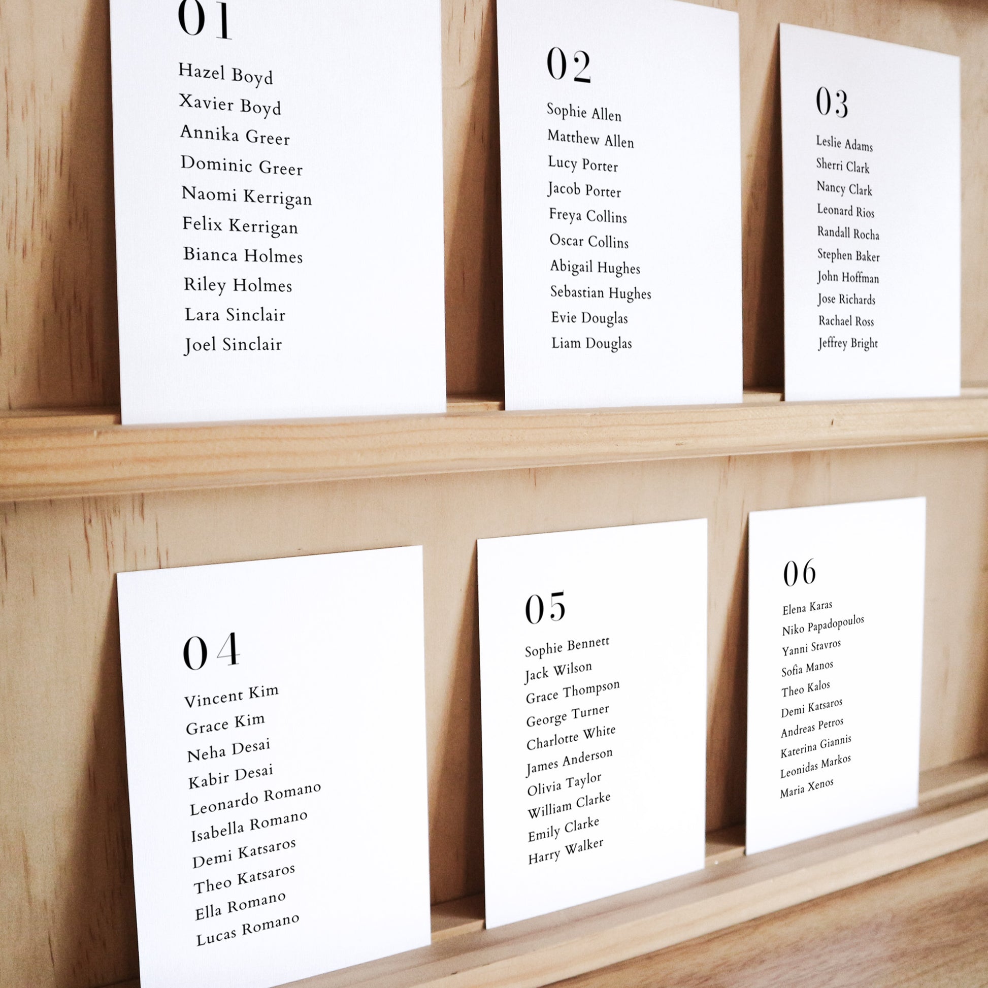 Set of six printable seating chart cards with names on a wooden display shelf.