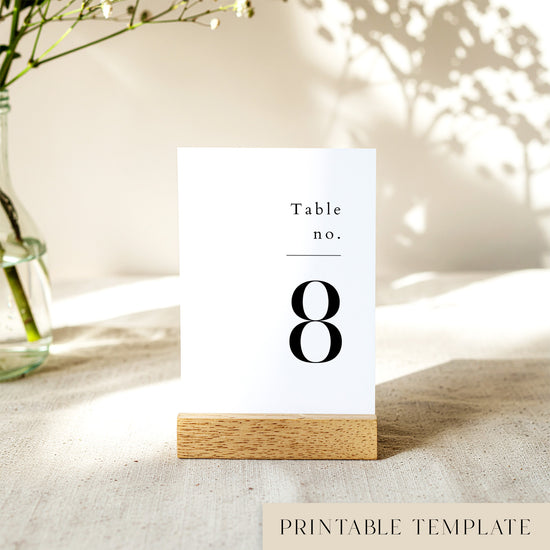 Printable table number card displayed on a wooden stand on a linen table cloth.