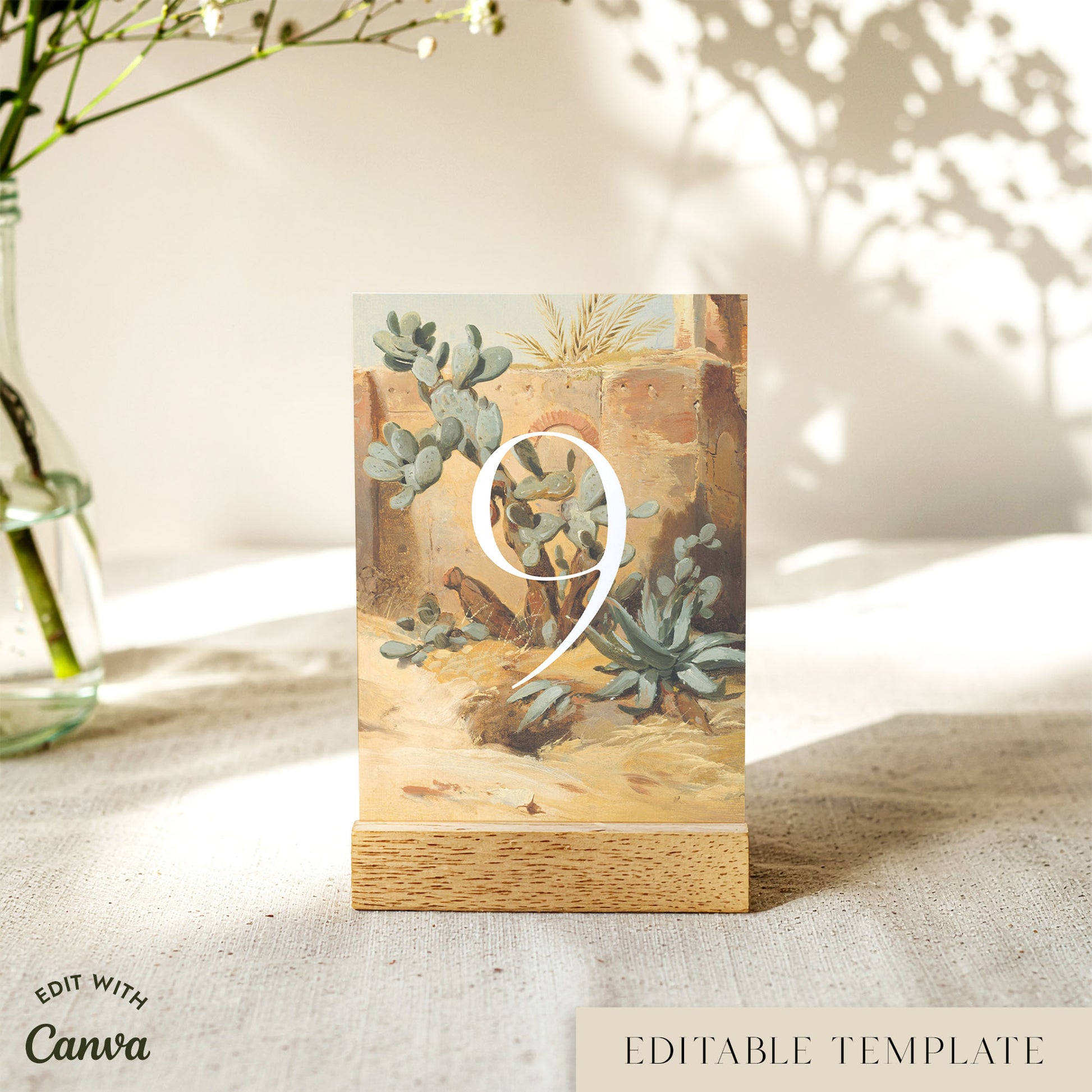 A rectangular printed table number card with a desert succulent illustration stands on a small wooden base on a tabletop. A large white numeral 9 is overlaid in the center.
