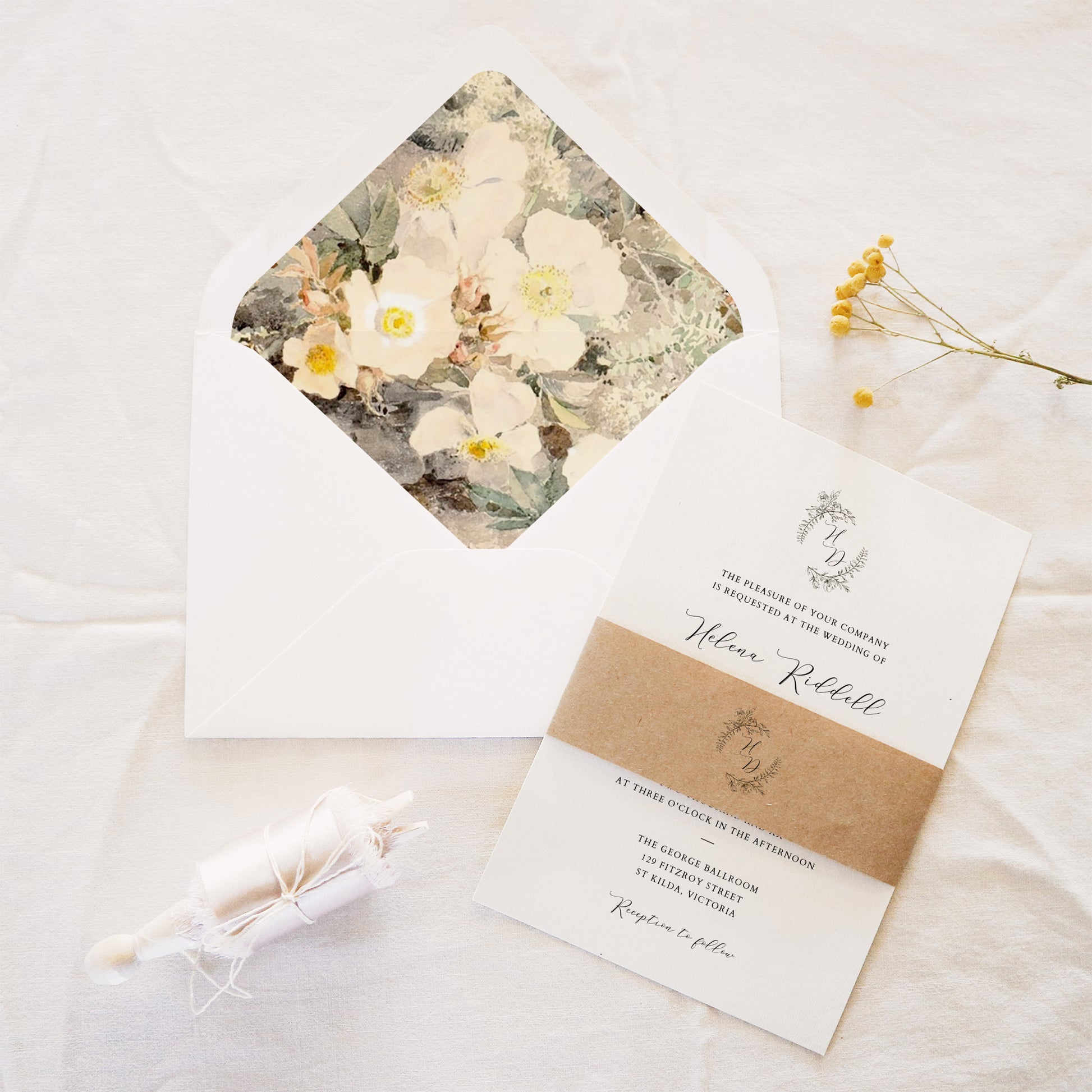 Wedding invitation set with floral design on the envelope and brown invitation belly band.