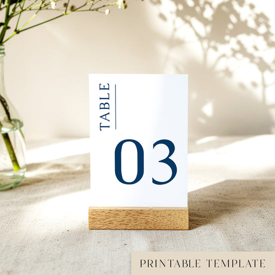 Printable table number card displayed on a wooden stand on a linen table cloth.