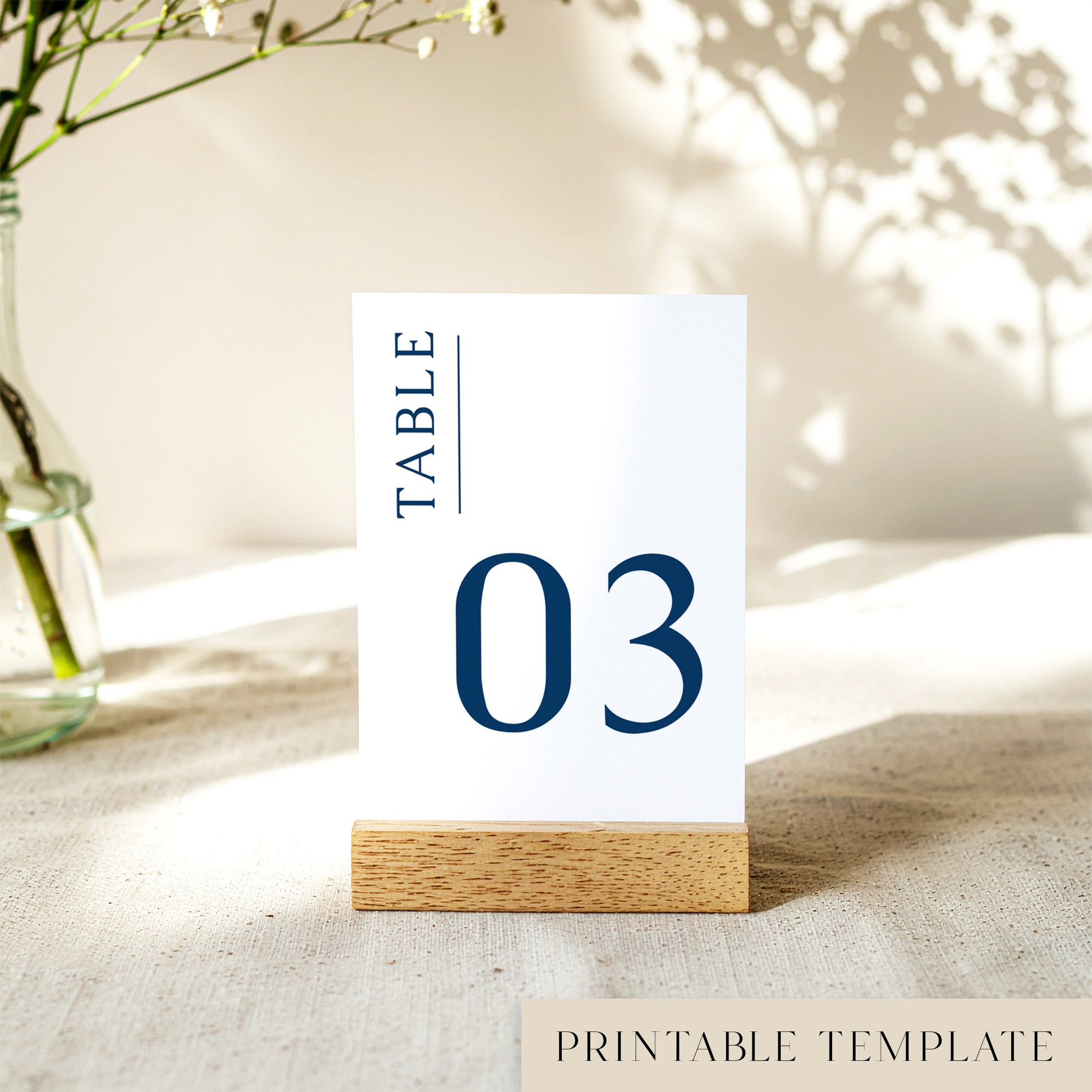 Printable table number card displayed on a wooden stand on a linen table cloth.