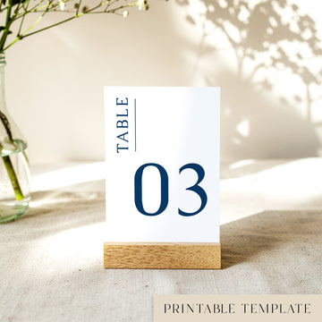 Printable table number card displayed on a wooden stand on a linen table cloth.