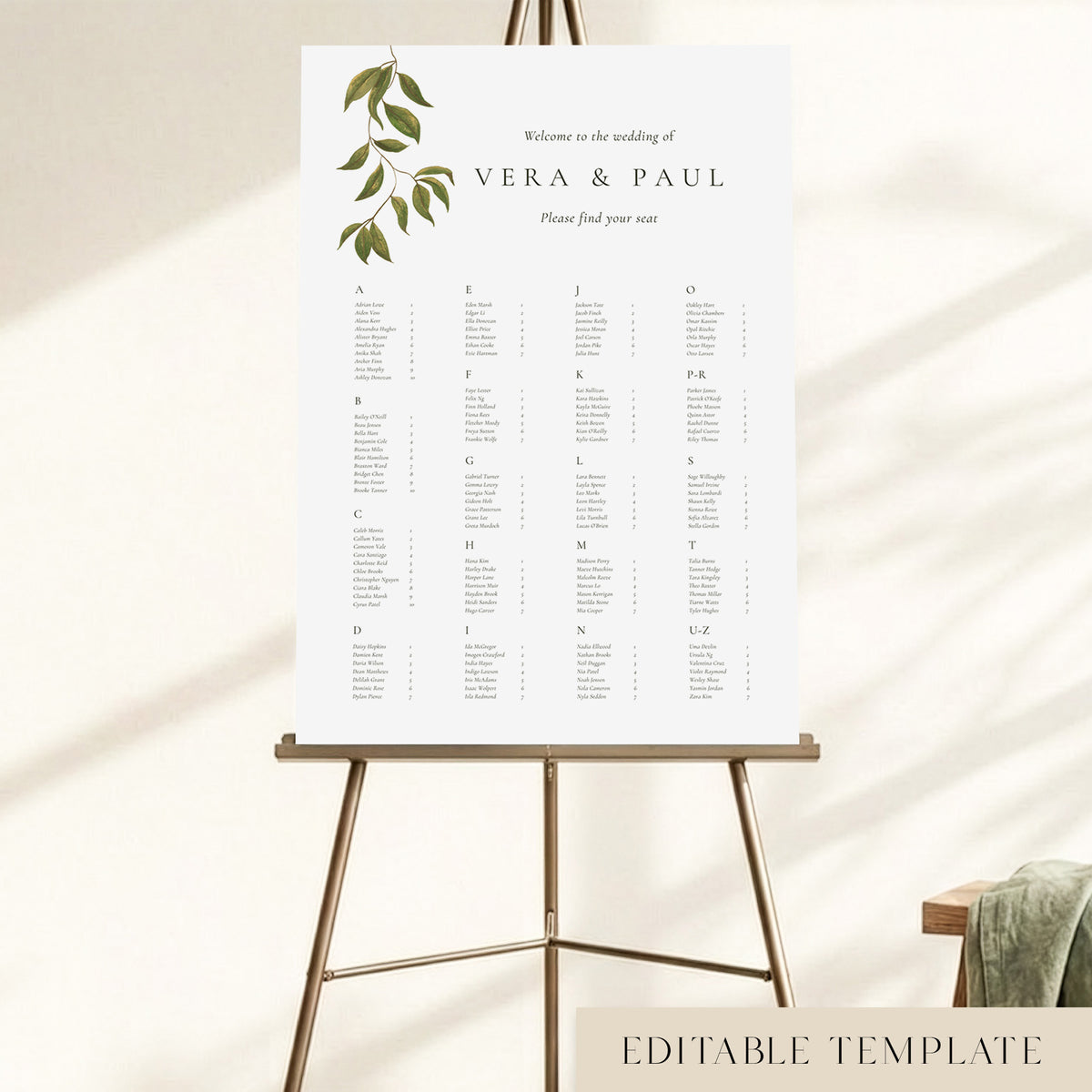 An A to Z wedding seating chart displayed on an easel, with hand-painted greenery and guest names