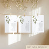 Three white seating chart cards with printed names and leaf design, clipped to a string with pegs, against a neutral background.