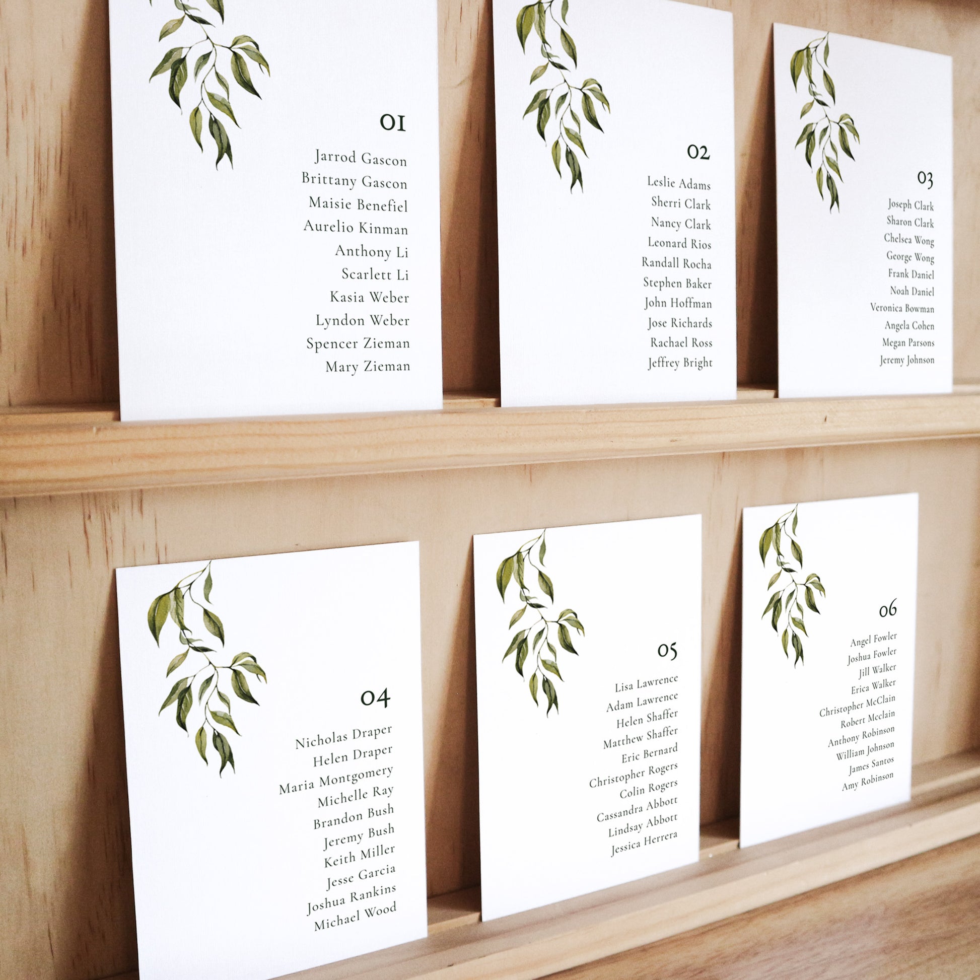 Set of six printable seating chart cards with names on a wooden display shelf.