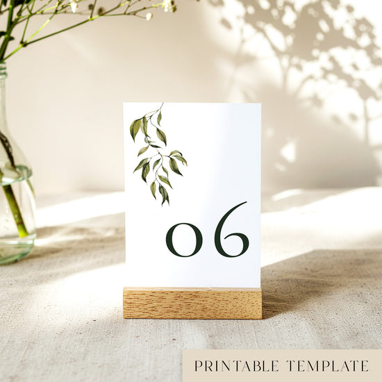 Printable table number card displayed on a wooden stand on a linen table cloth.
