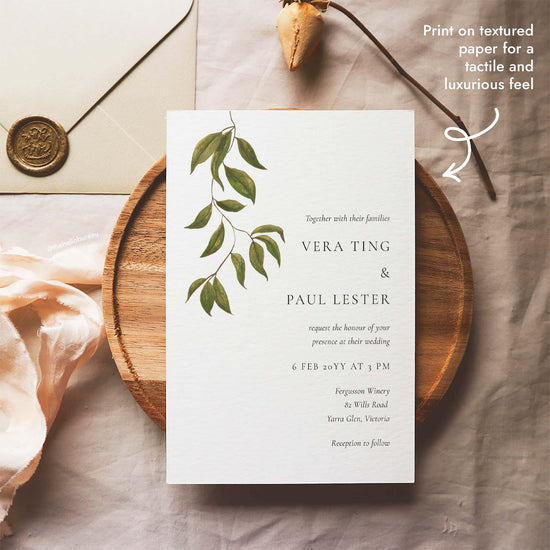 Editable botanical wedding invitation template featuring hand-painted foliage, styled beside a wax-sealed envelope, printable on textured paper for a tactile feel.