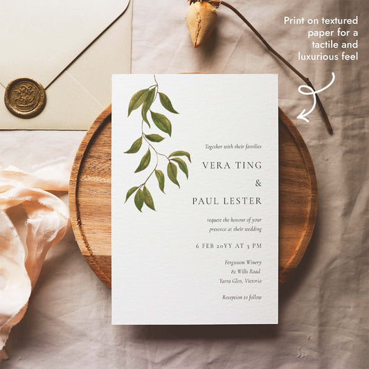 Editable botanical wedding invitation template featuring hand-painted foliage, styled beside a wax-sealed envelope, printable on textured paper for a tactile feel.