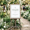 Elegant greenery engagement party welcome sign displayed in a timber frame on a wooden easel