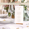 Wedding bar menu card with drink options on a wooden holder sitting on a white table cloth with flowers, plates and wine glasses.
