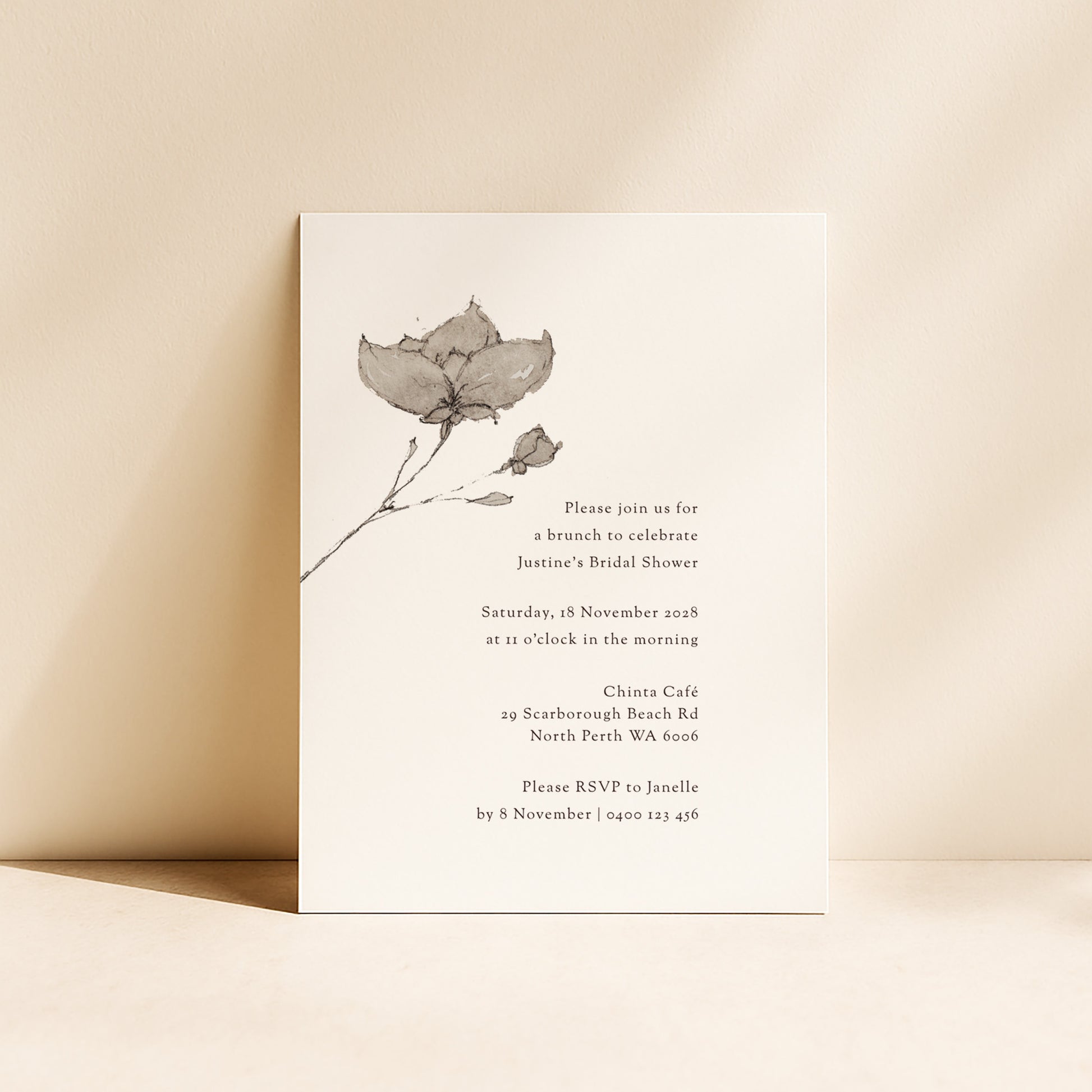 Bridal shower invitation with floral design standing upright on a beige background.