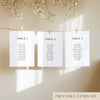 Three white seating chart cards with printed names, clipped to a string with pegs, against a neutral background.