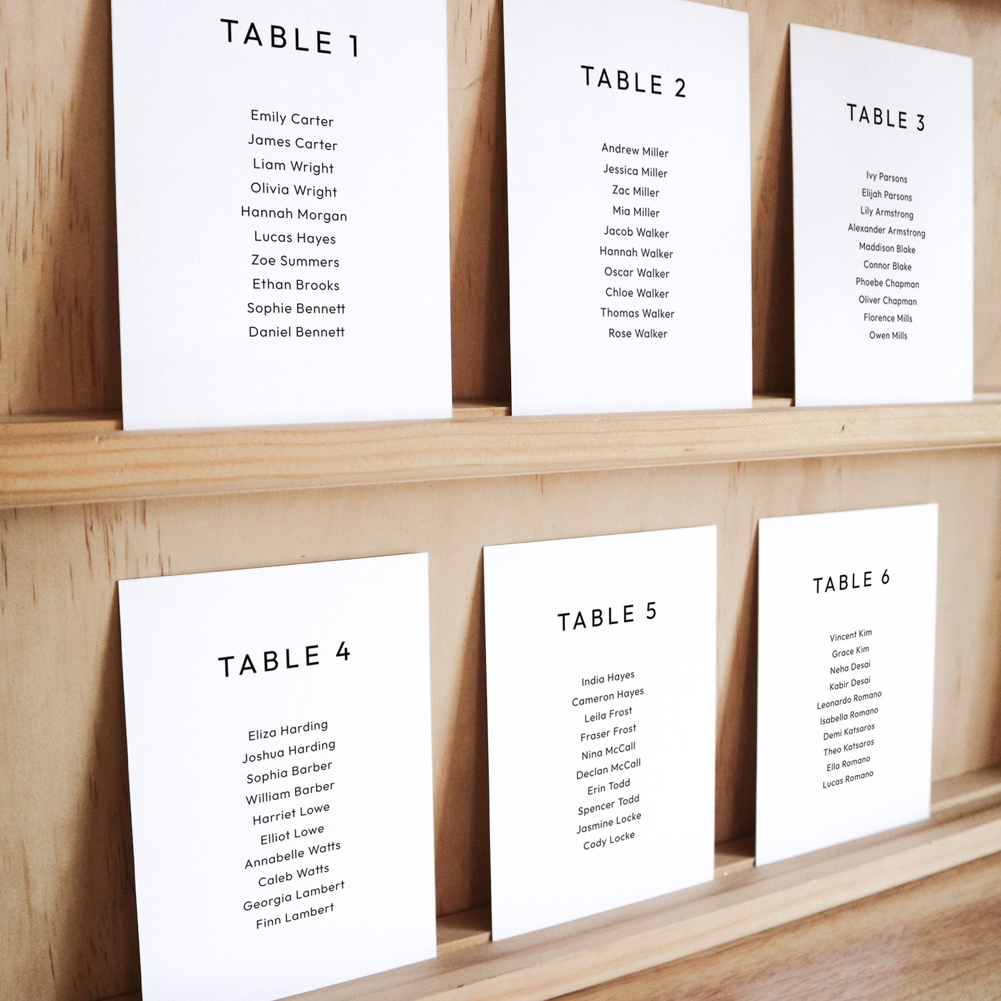 Set of six printable seating chart cards with names on a wooden display shelf.