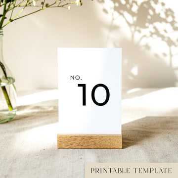 Printable table number card displayed on a wooden stand on a linen table cloth.