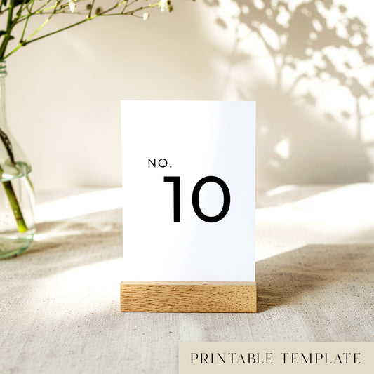 Printable table number card displayed on a wooden stand on a linen table cloth.