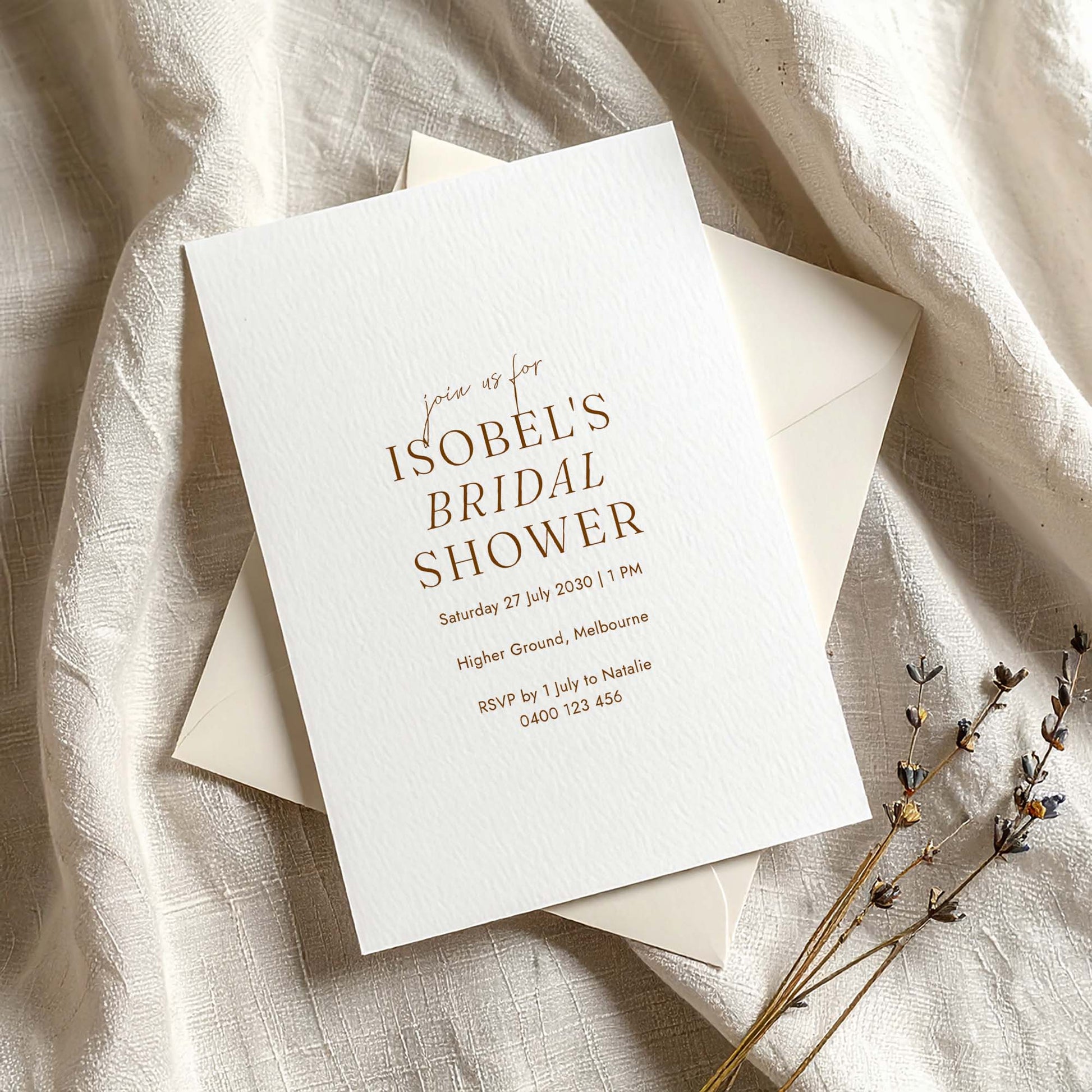 Minimal bridal shower invitation on textured card with envelope on fabric background.