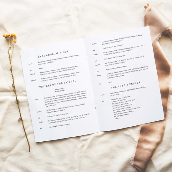 Open A5 church wedding ceremony booklet displaying text on a neutral fabric background.