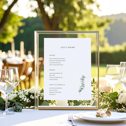 Acrylic framed bar menu on a table with an outdoor wedding setting.