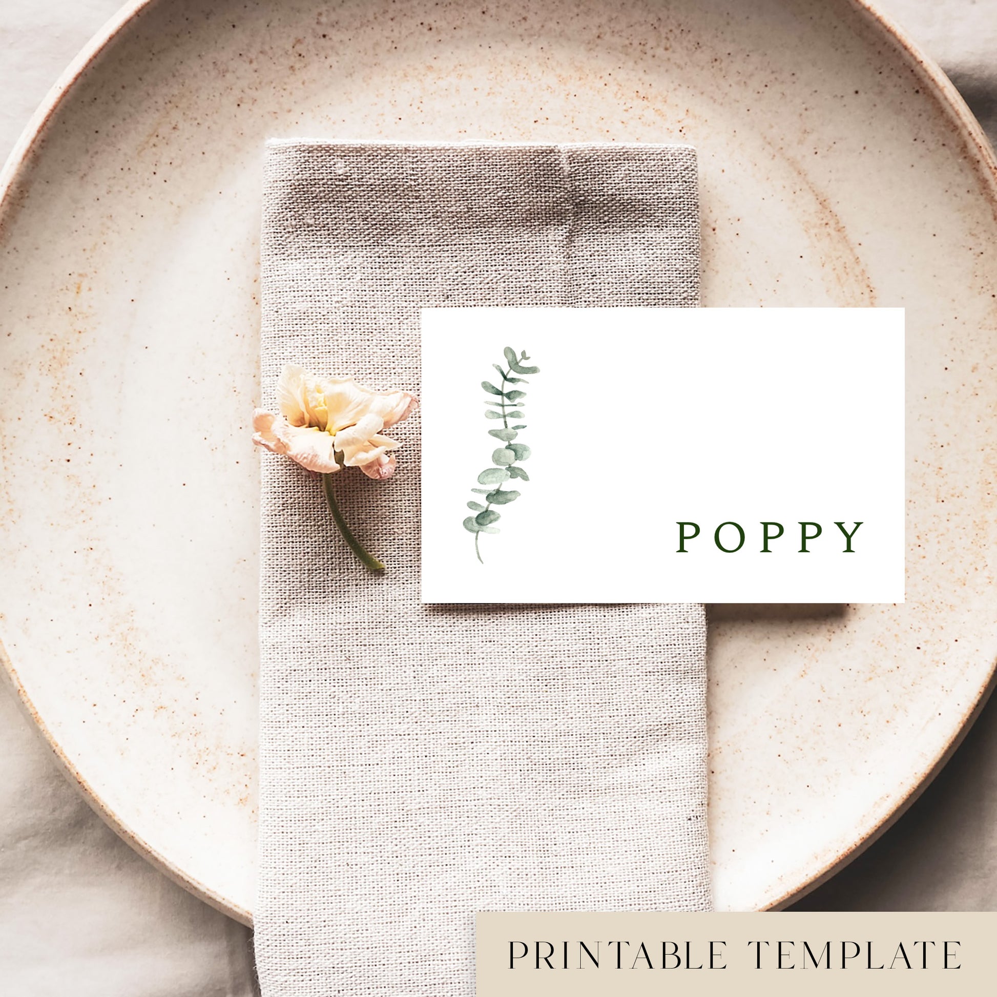 A flat place card with a name printed on it, positioned on a plate with a napkin and a floral decoration.