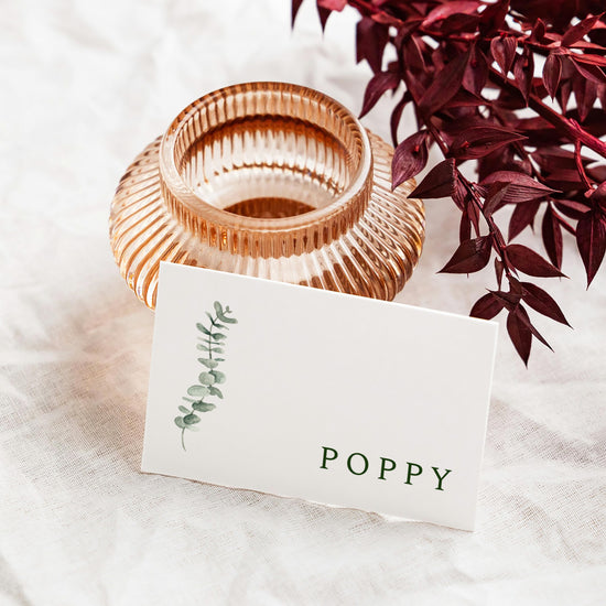 Rose gold candle holder with a flat place card leaning against it.